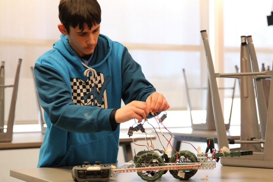 Junior Cory Starr connecting a battery to his robot.