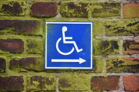 A wheelchair sign pasted on a brick wall.