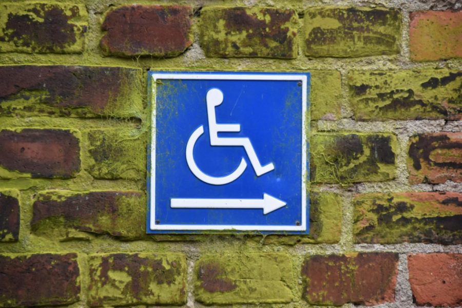 A wheelchair sign pasted on a brick wall.